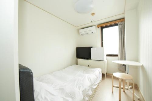 een kleine kamer met een bed, een tafel en een raam bij Hotel Empire in Shinjuku in Tokyo