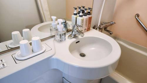 a white bathroom with a sink and a mirror at Hotel Paco Obihiro Ekimae in Obihiro
