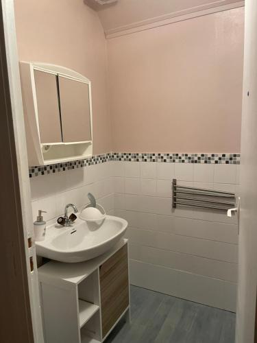 a white bathroom with a sink and a mirror at Maison Entre Terre et Mer in Primelin
