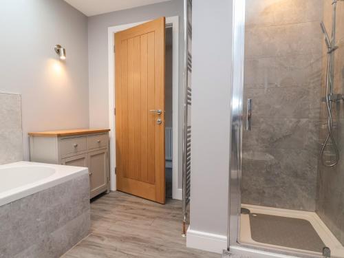a bathroom with a shower and a tub and a sink at Naseby House in Alfreton