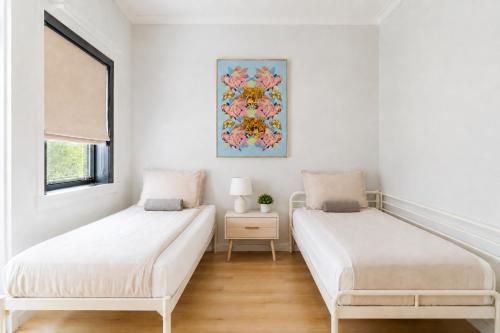 two beds in a white room with a picture on the wall at The Cozy Oslo Stay in Oslo