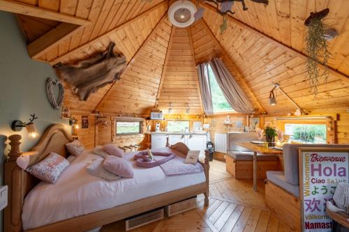 a bedroom with a large bed in a wooden cabin at Cabane Kota Désiré, bain nordique in Saint Die