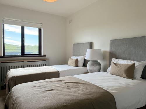 two beds in a white room with a window at Dough Lodge in Lahinch
