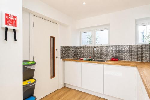 a kitchen with white cabinets and a sink at 6 En-Suites with 7 Beds Near Arena & City in Nottingham