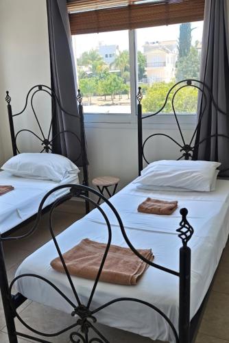 two twin beds in a room with a window at Sunset Green 01 in Paphos