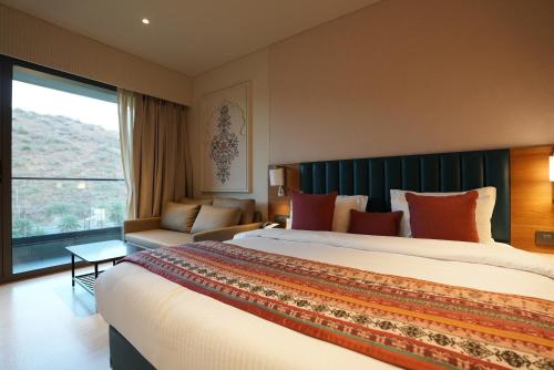 a hotel room with a large bed and a large window at Seasons Park Resort in Udaipur