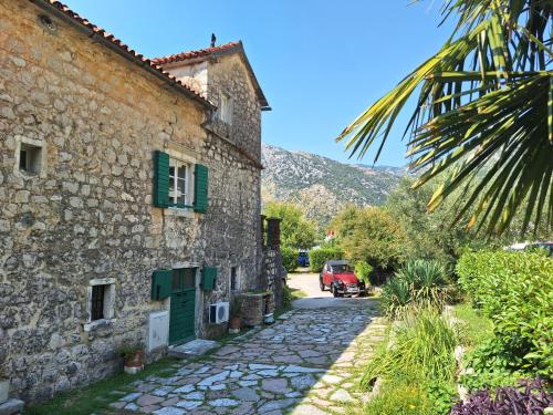 an old stone house with green shutters and a palm tree at Apartments Subotic in Risan