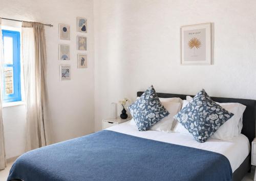 a bedroom with a bed with blue and white pillows at Garden Residence Andros with Sea View & Pool in Gavrio