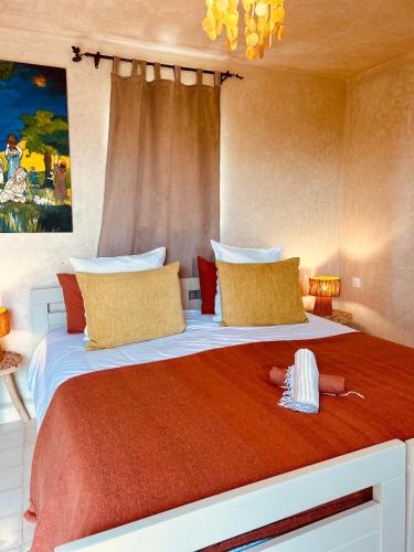 a bedroom with a large bed with red sheets and yellow pillows at Yogam villa Essaouira in Al Ghar