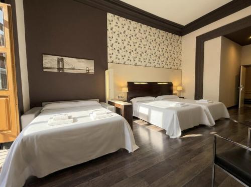 a room with three beds with white sheets at Alhambra Suites in Madrid