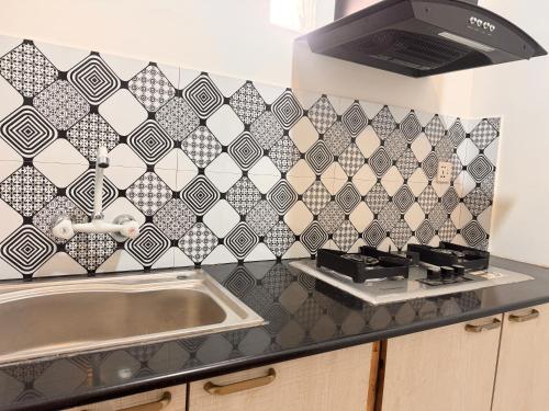 a kitchen with a sink and a black and white tiled wall at Sable d'Or Résidence by Star 'A' in Karachi