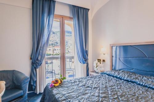 a bedroom with a blue bed and a window at Aragona Palace Hotel & Spa in Ischia Town
