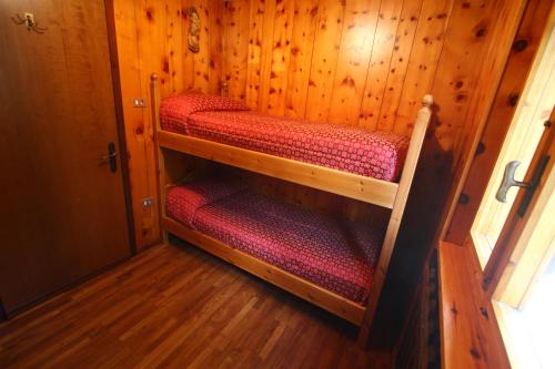 a room with three bunk beds in a wooden room at Champoluc Apartment in Champoluc
