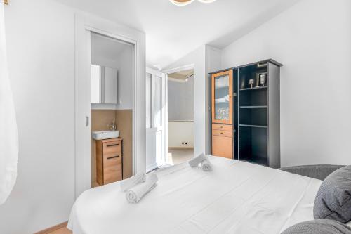 a bedroom with a white bed and a kitchen at Charming Casa Piccola in Draga Bašćanska