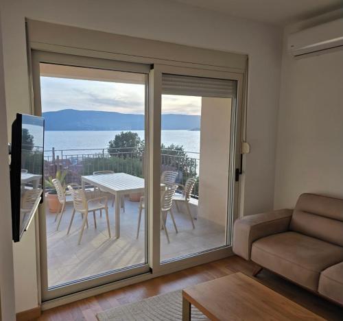 a living room with a sliding glass door with a table and chairs at Stan Kumbor sa dvije spavace sobe in Kumbor