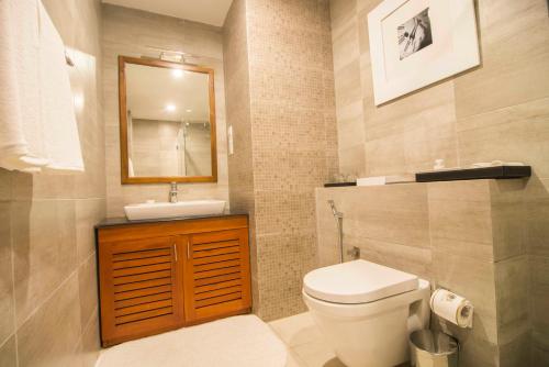 ein Badezimmer mit einem WC, einem Waschbecken und einem Spiegel in der Unterkunft Platinum One Suites in Colombo