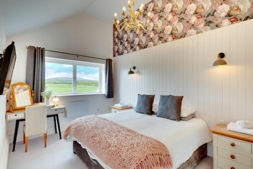 a bedroom with a bed and a desk and a window at Gardener's Cottage in Alnwick