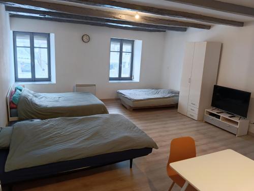a room with two beds and a tv and a table at Studios à la Campagne in Neuilly-lʼÉvêque