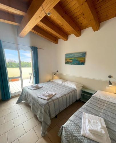 a bedroom with two beds and a large window at Hotel Garni Tosca in Lido di Jesolo