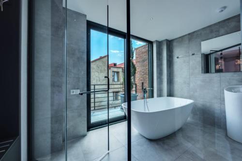 a bathroom with a tub and a glass wall at Mit Hotel Tbilisi in Tbilisi City