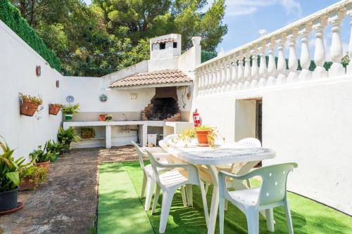 a patio with a table and chairs on the grass at Hauzify I Casa Peralta in Les tres Cales