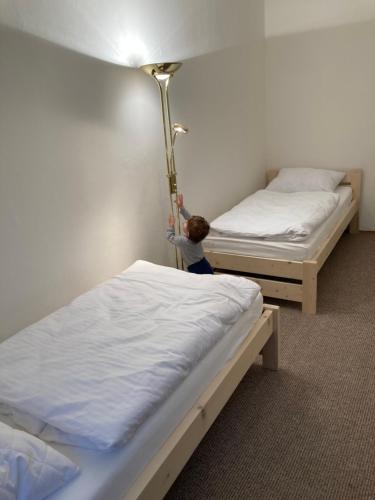 a small child is standing between two beds at Apartmány u Arény Ostrava in Ostrava
