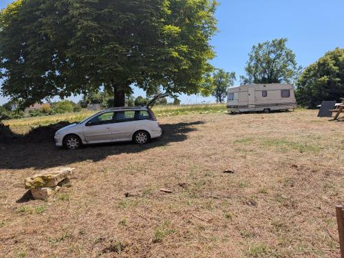 a small car parked in a field next to a trailer at Au soleil in Virac