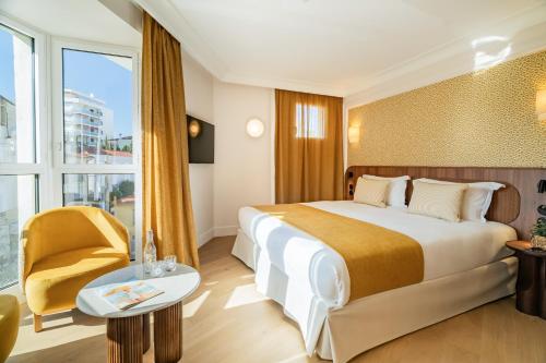 a hotel room with a large bed and a chair at Hôtel Lepoussin in Cannes