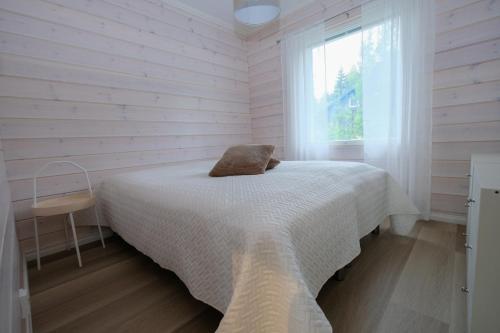a white bedroom with a bed and a window at Villa Arvonpiha A in Tahkovuori