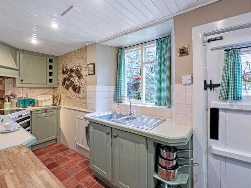 a kitchen with green cabinets and a sink at Ruffles Cottage Dunster in Dunster