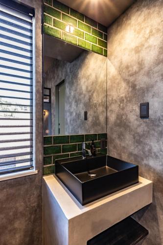 a bathroom with a black sink and green tiles at UG HOSTEL Takayama in Takayama