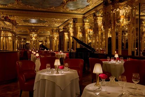 a restaurant with white tables and red chairs at Hotel Cafe Royal in London