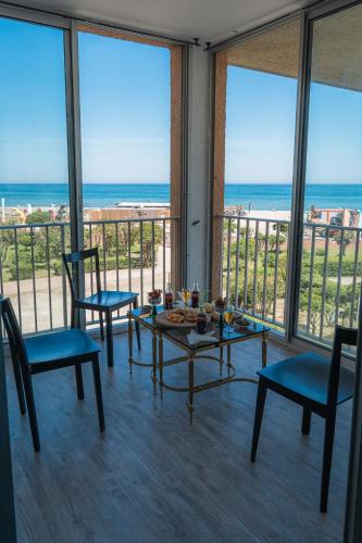 a room with a table and chairs and the ocean at Le Lydia - Duplex - Vue Mer - Accès direct Plage - Parking - Barbecue in Le Barcarès