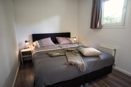a bedroom with a large bed with pillows and a window at Park Berkenrhode in Wekerom