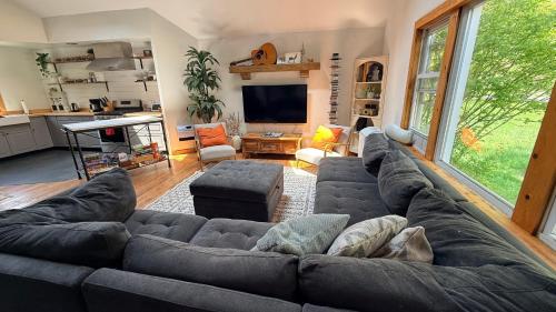 a living room with a large couch and a kitchen at Cheerful 3-bedroom cabin with mountain view in East Jewett