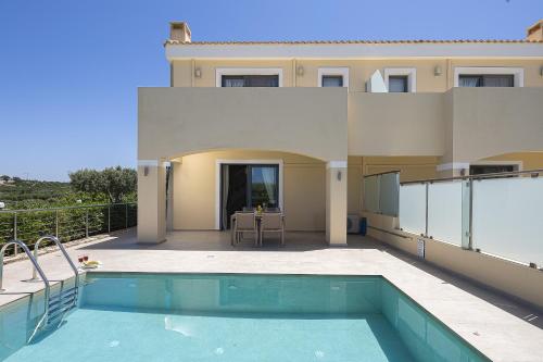 a house with a swimming pool on a patio at Carme Villas in Adelianos Kampos