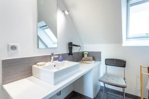 a bathroom with a white sink and a chair at Entre mer et rivière in Moëlan-sur-Mer