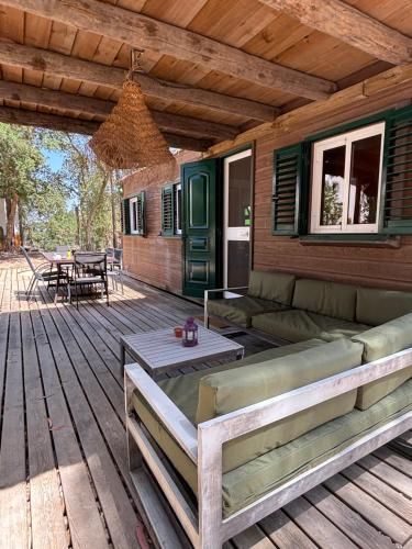 a porch with a couch and a table on a wooden deck at Casa Silvestre in Melides