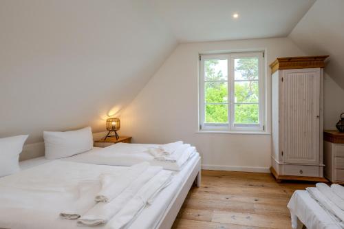 a white bedroom with a large bed and a window at Traumgarten Haus Leichte Brise in Prerow