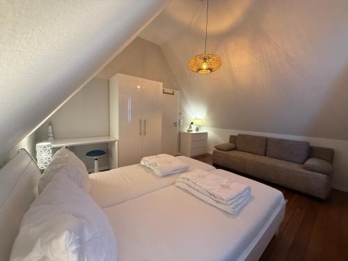 a bedroom with a white bed and a couch at Ferienhaus Sarcander in Glowe