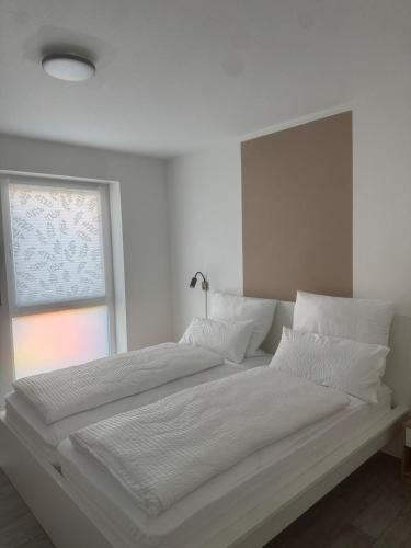 a white bed with white sheets and a window at Lingen Stay 2 in Lingen