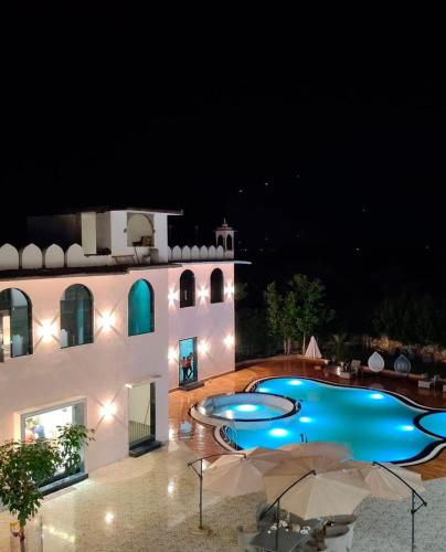 a swimming pool in front of a building at night at Shiv Resort & Palace in Shivpurī