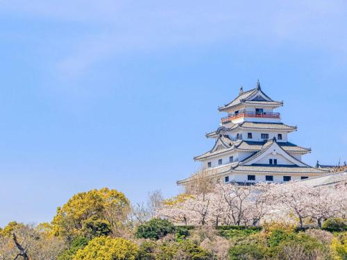 a tall white building withakura trees in front of it at Mercure Saga Karatsu Resort in Karatsu