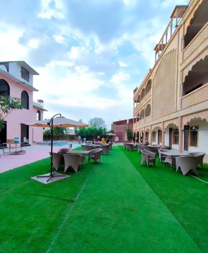 a courtyard with tables and chairs on green grass at Shiv Resort & Palace in Shivpurī