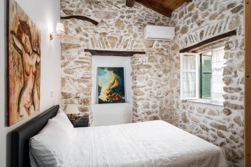 a stone walled bedroom with a bed and a painting at Art House Near to Saint George Beach by Konnect in Págoi