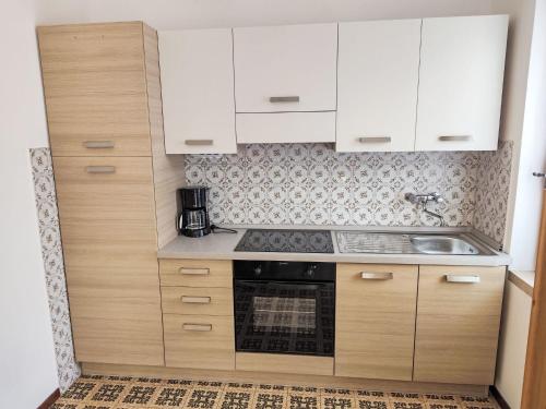 a small kitchen with white cabinets and a sink at Apartment Villa Martinelli-1 by Interhome in Crone