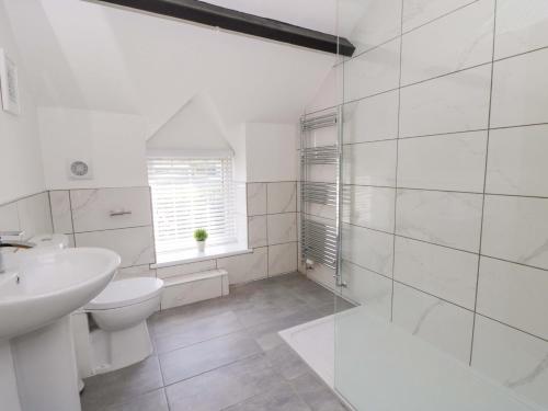 a white bathroom with a sink and a toilet at Rosemary Cottage 1 in Tywyn