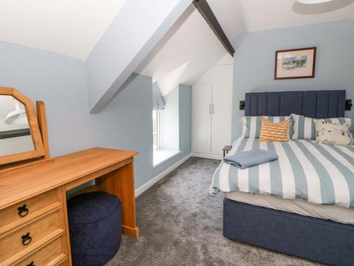 a bedroom with a bed and a desk and a mirror at Rosemary Cottage 1 in Tywyn
