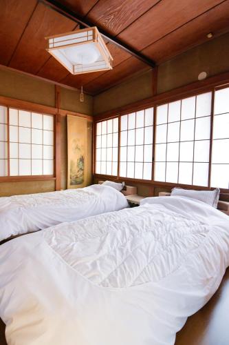 a room with three large white beds with windows at Re-home in Izunokuni