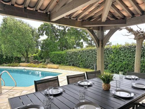 a table with plates and glasses on it next to a pool at Holiday Home Gisèle by Interhome in Saint-Aygulf
